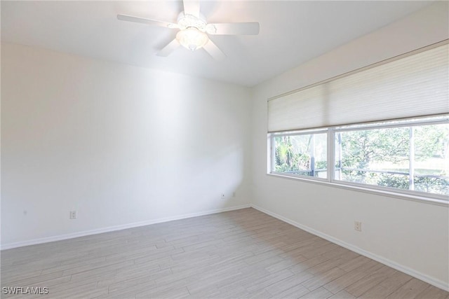 spare room featuring baseboards, light wood-style flooring, and a ceiling fan