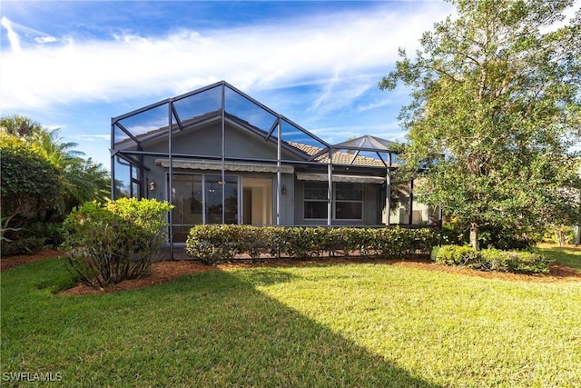 rear view of house featuring a lanai and a yard