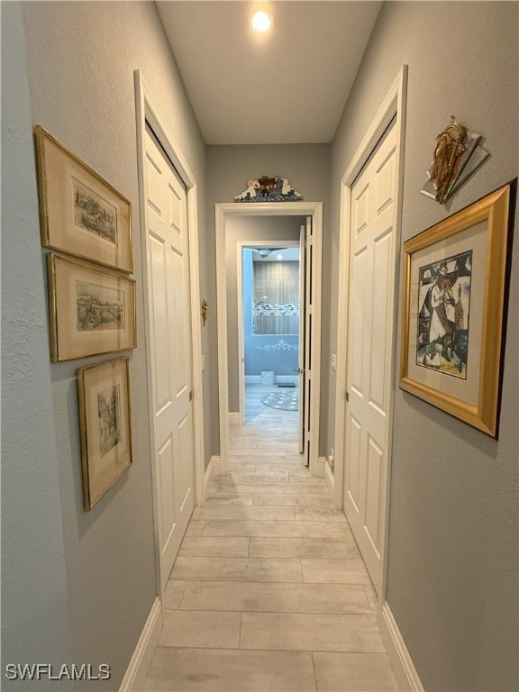 corridor featuring wood tiled floor and baseboards