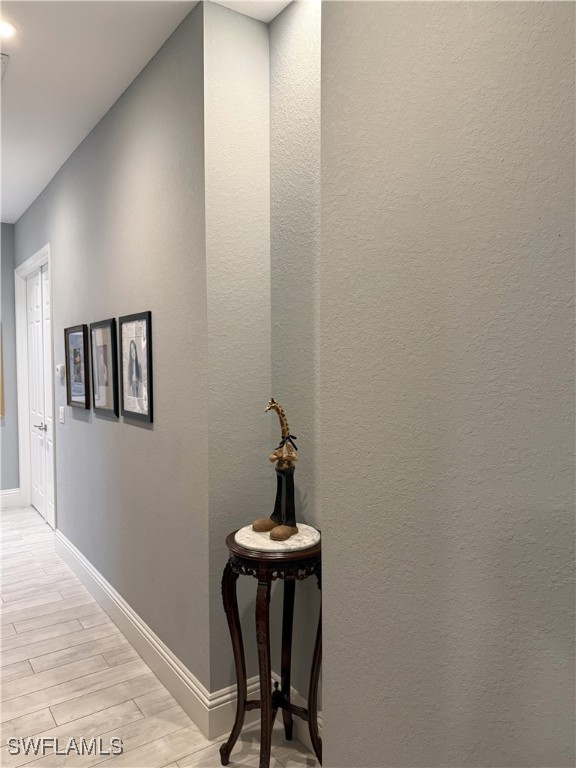 corridor featuring wood tiled floor and baseboards