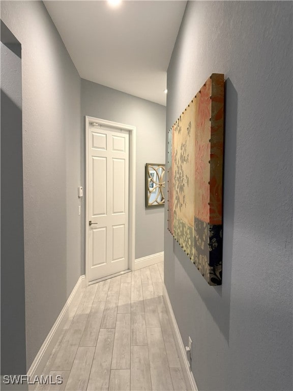 corridor with light wood finished floors and baseboards