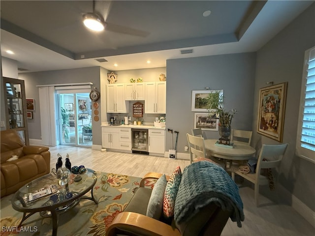 living room with beverage cooler, visible vents, and a tray ceiling