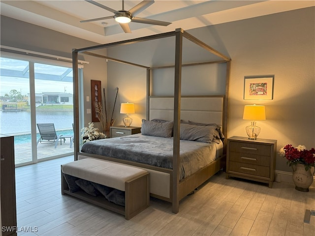 bedroom featuring a water view, access to exterior, and light wood finished floors