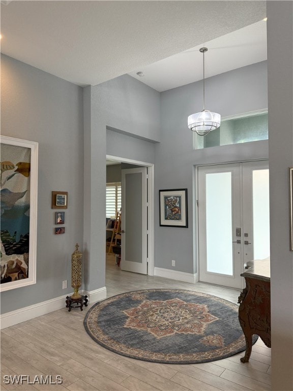 entryway with a towering ceiling, baseboards, and wood finished floors