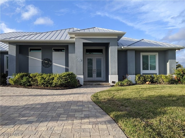 doorway to property featuring french doors, metal roof, a standing seam roof, and stucco siding