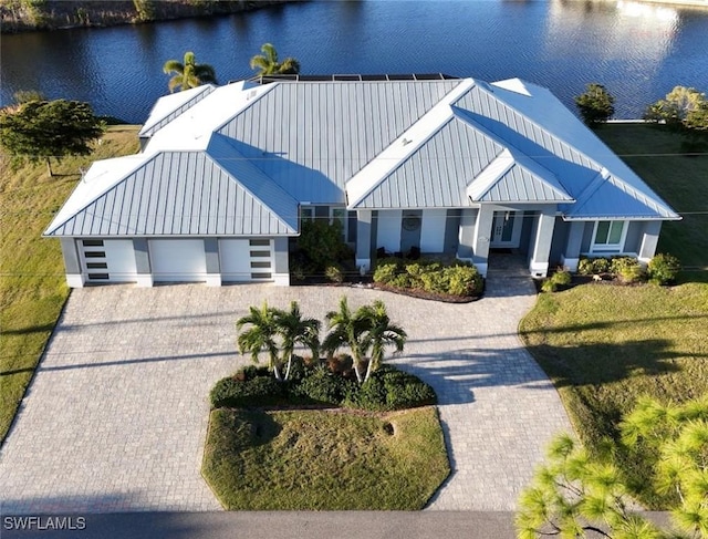 modern farmhouse style home featuring decorative driveway, a water view, metal roof, and a standing seam roof