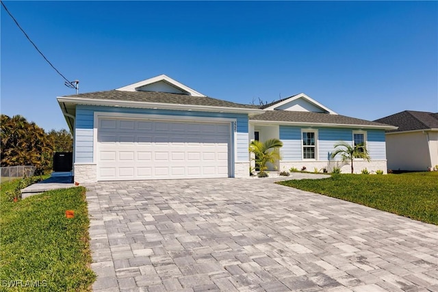 ranch-style home featuring a garage, stone siding, decorative driveway, and a front yard