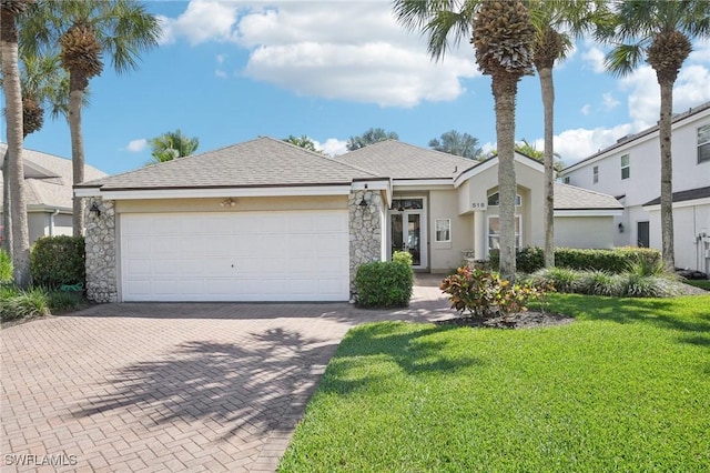 view of front of property featuring an attached garage, stone siding, decorative driveway, stucco siding, and a front yard