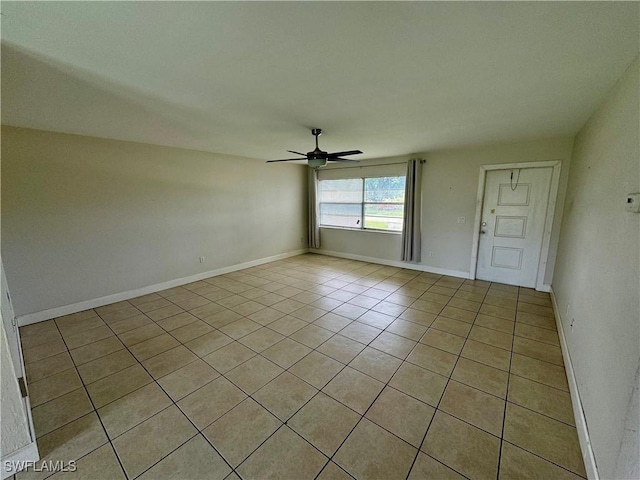 spare room featuring a ceiling fan, baseboards, and light tile patterned floors