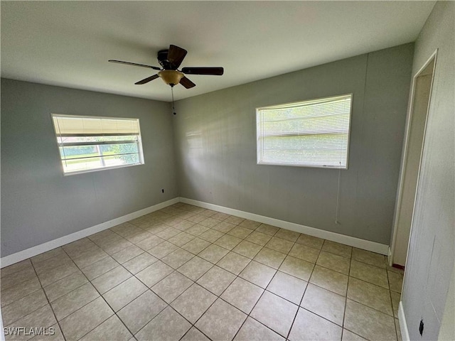 spare room featuring light tile patterned floors, a ceiling fan, and baseboards