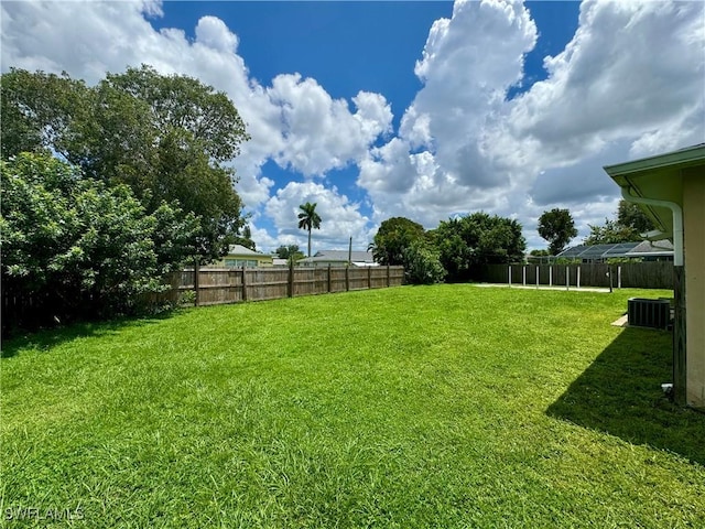 view of yard featuring fence and central AC