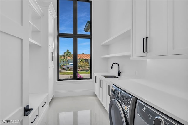 laundry area with cabinet space, baseboards, a sink, and independent washer and dryer