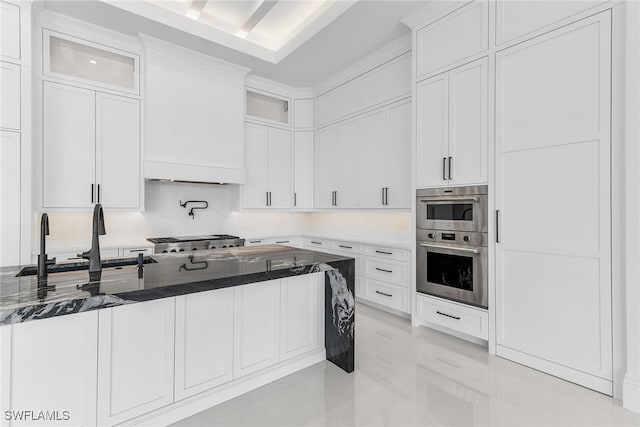 kitchen with dark stone counters, glass insert cabinets, a sink, and white cabinetry