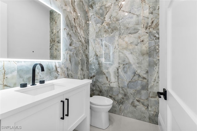 bathroom featuring toilet, vanity, and tile walls