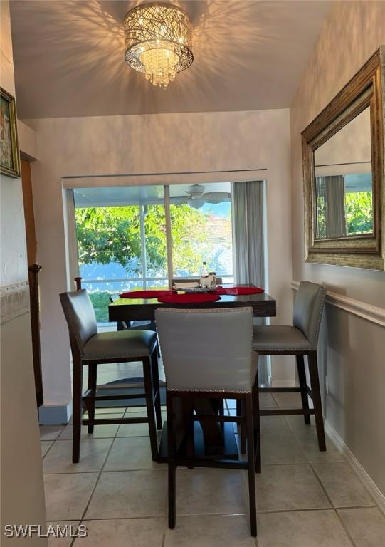 dining area featuring light tile patterned floors, plenty of natural light, and an inviting chandelier