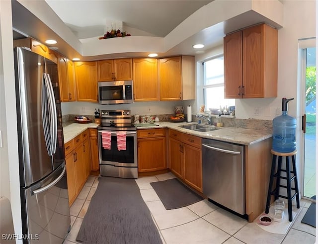 kitchen with vaulted ceiling, stainless steel appliances, light tile patterned floors, and a sink