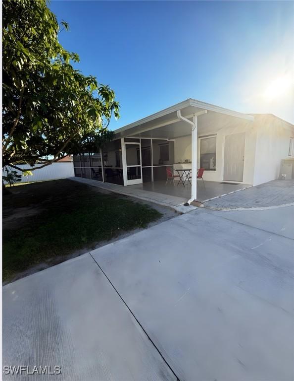 back of property featuring a sunroom, stucco siding, and a patio