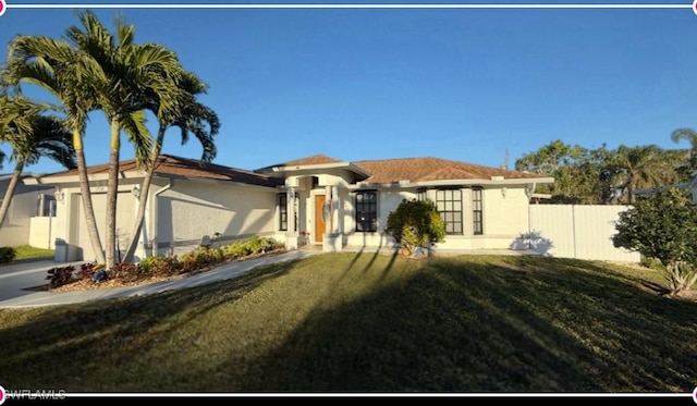 mediterranean / spanish house with a garage, a front yard, fence, and stucco siding