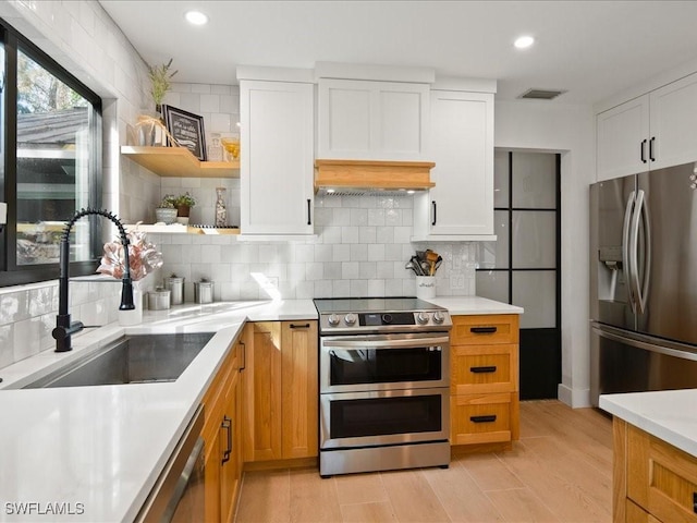 kitchen featuring tasteful backsplash, visible vents, appliances with stainless steel finishes, light countertops, and a sink