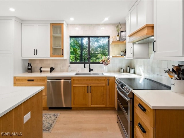 kitchen with white cabinetry, appliances with stainless steel finishes, backsplash, and a sink