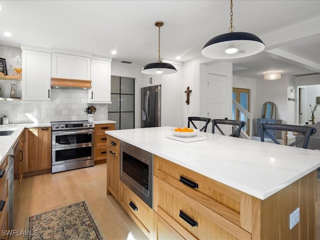 kitchen with tasteful backsplash, pendant lighting, stainless steel appliances, light wood-type flooring, and open shelves