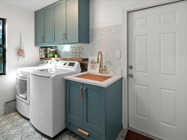 clothes washing area with cabinet space, independent washer and dryer, and a sink