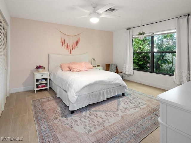 bedroom featuring ceiling fan, light wood finished floors, visible vents, and baseboards