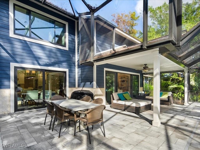 exterior space with outdoor dining area, glass enclosure, an outdoor living space, and a ceiling fan