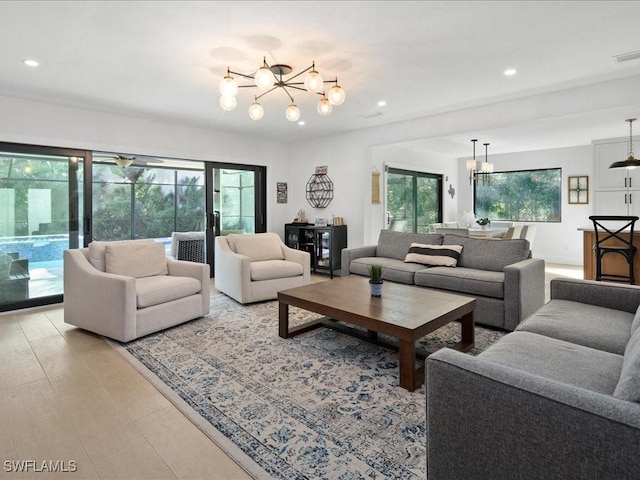 living room featuring light wood-style flooring, visible vents, a notable chandelier, and recessed lighting