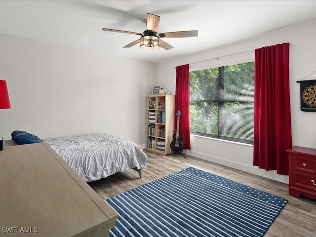 bedroom featuring a ceiling fan, baseboards, and wood finished floors