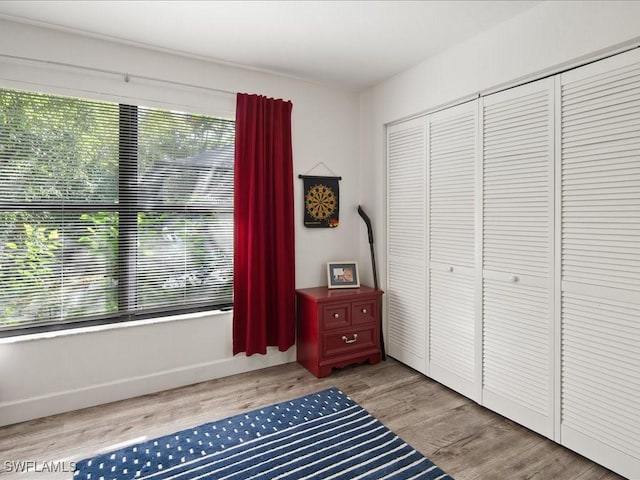 bedroom with a closet, wood finished floors, and baseboards