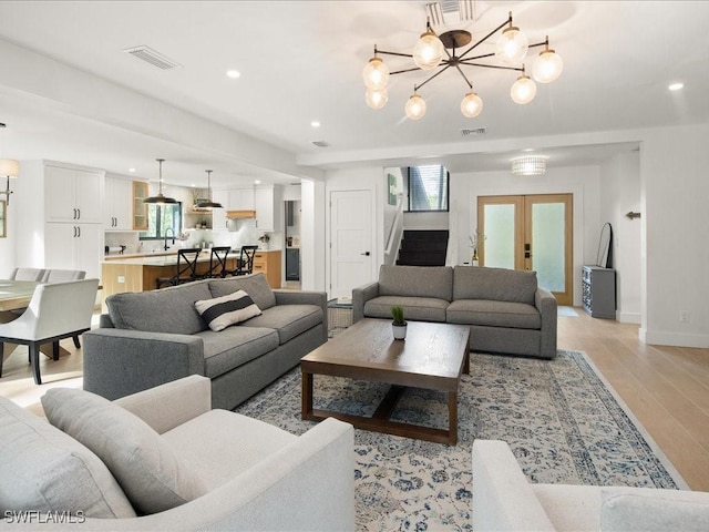 living area with light wood-type flooring, french doors, visible vents, and stairway