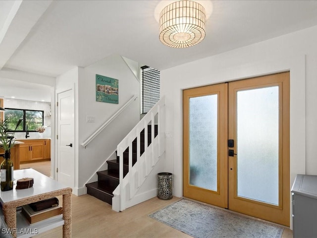 entrance foyer featuring light wood-style flooring, french doors, and stairway