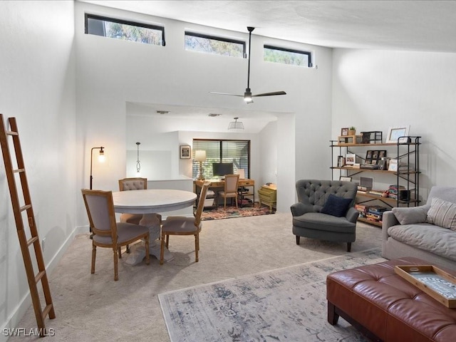 living room featuring plenty of natural light, a towering ceiling, and light colored carpet