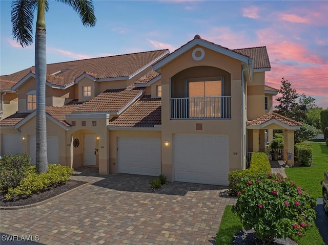 28621 Carriage Home Dr Unit 204, Bonita Springs, FL 34134 - mediterranean / spanish house featuring a tiled roof, stucco siding, decorative driveway, a garage, and a balcony