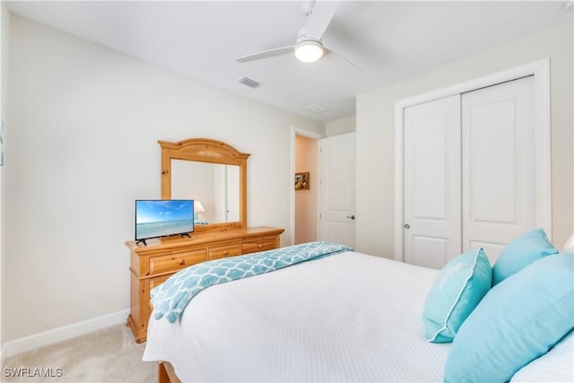 bedroom with visible vents, baseboards, ceiling fan, light colored carpet, and a closet