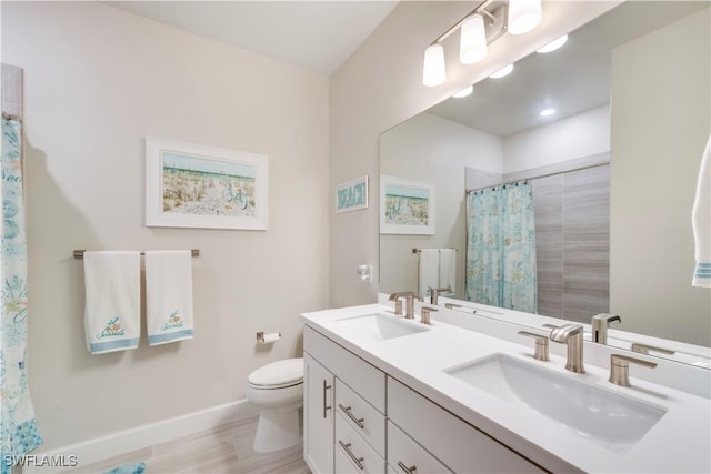 full bath with double vanity, toilet, baseboards, and a sink