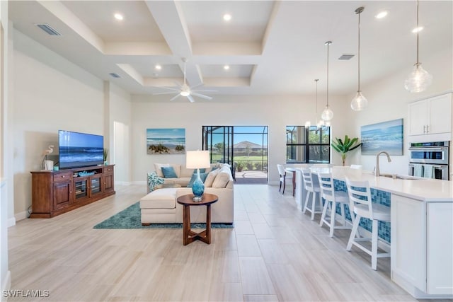 living area with visible vents, baseboards, a high ceiling, and coffered ceiling