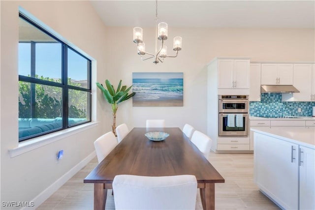 dining room featuring a chandelier, light wood finished floors, and baseboards