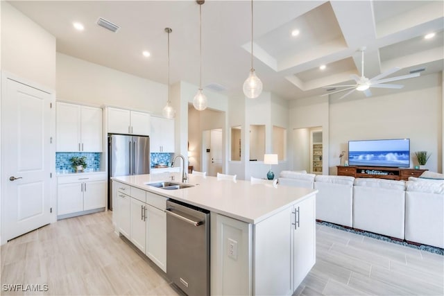 kitchen featuring visible vents, a sink, open floor plan, a high ceiling, and appliances with stainless steel finishes