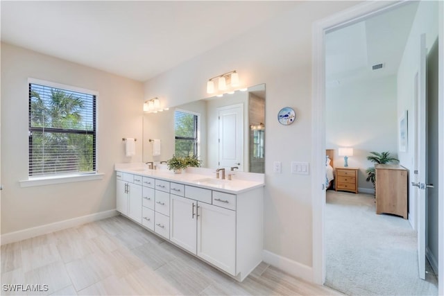 ensuite bathroom featuring a sink, visible vents, connected bathroom, and double vanity