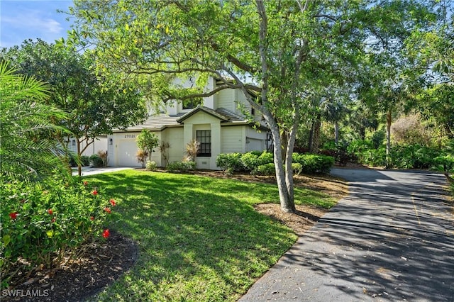 view of front of house with aphalt driveway, a garage, and a front lawn