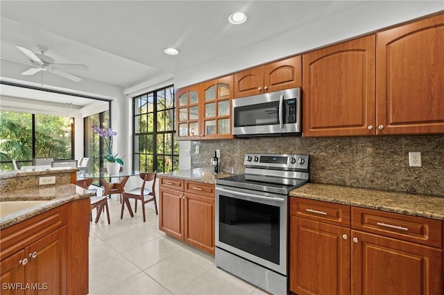 kitchen featuring light stone counters, backsplash, appliances with stainless steel finishes, and light tile patterned floors