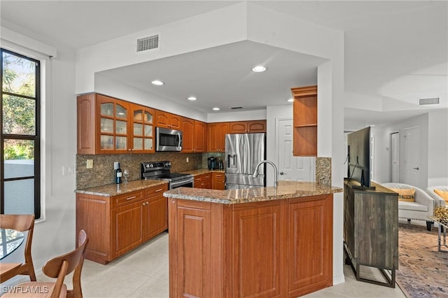 kitchen with visible vents, brown cabinets, a peninsula, and stainless steel appliances