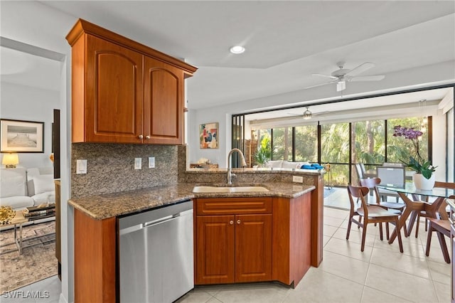 kitchen with backsplash, dishwasher, dark stone counters, brown cabinets, and a sink