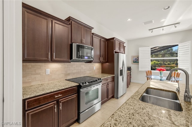 kitchen with decorative backsplash, light stone counters, appliances with stainless steel finishes, and a sink