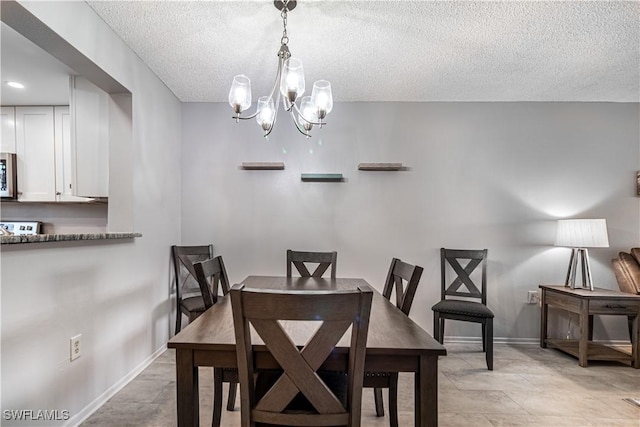 dining area featuring a textured ceiling, baseboards, and an inviting chandelier