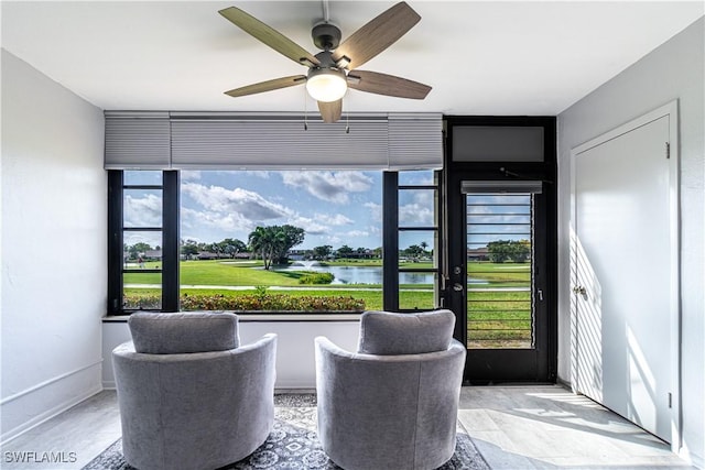 interior space featuring a ceiling fan, stone finish flooring, a water view, and baseboards