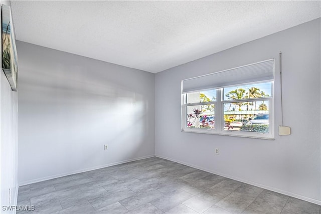 spare room featuring baseboards and a textured ceiling