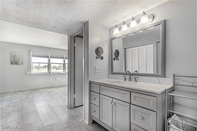 bathroom featuring baseboards, a textured ceiling, and vanity